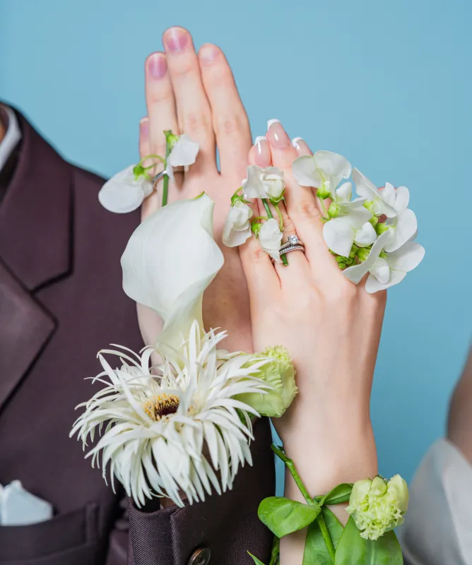 結婚指輪をつけ白い花を添えた新郎新婦の重なる手元（Hands with flowers シーン）