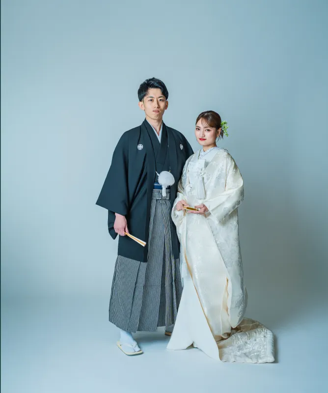 黒紋付袴の新郎と白無垢の花嫁が並ぶ全身（和装シーン）