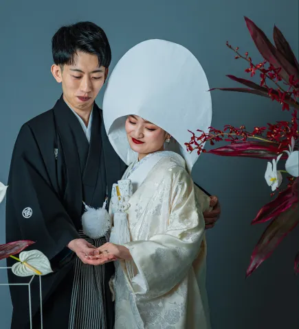 綿帽子に白無垢の花嫁と寄り添う黒紋付の新郎（和装シーン）